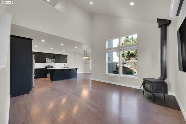 living area featuring dark wood finished floors, recessed lighting, a wood stove, high vaulted ceiling, and baseboards