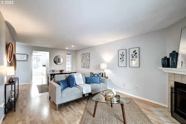 living room with a tiled fireplace and light hardwood / wood-style flooring