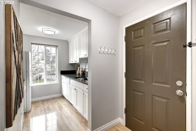 bar with dishwasher, sink, white cabinets, fridge, and light hardwood / wood-style flooring