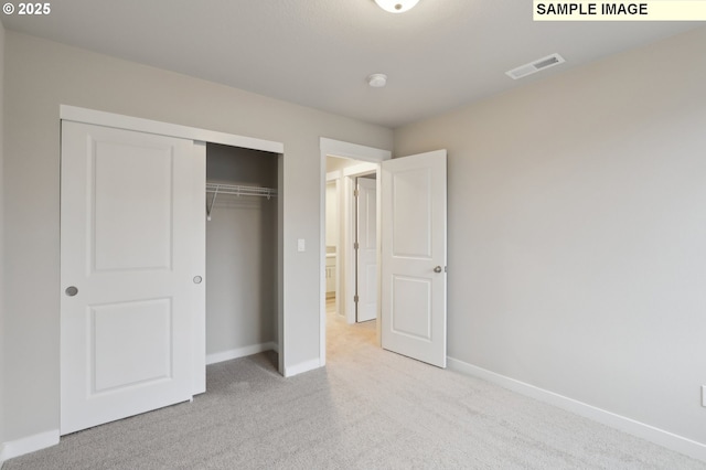 unfurnished bedroom featuring carpet, visible vents, a closet, and baseboards