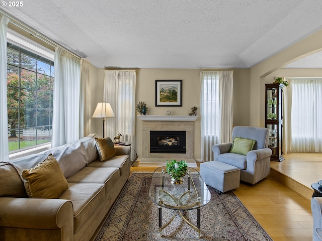 living room featuring a high end fireplace, a textured ceiling, and wood finished floors