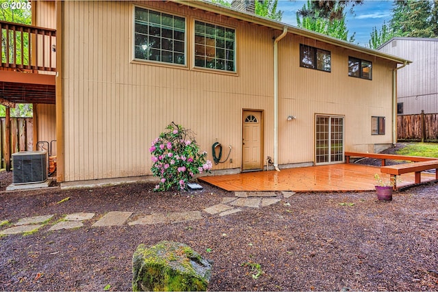 rear view of property featuring a deck, central AC, and fence
