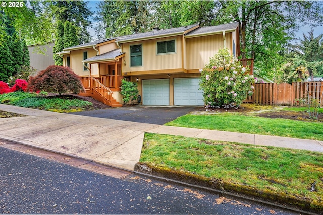 split foyer home featuring driveway, fence, and an attached garage