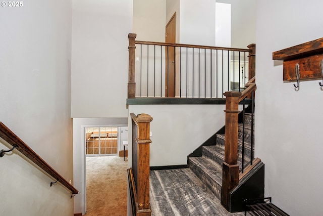 stairway with carpet flooring, a towering ceiling, and baseboards
