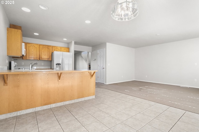 kitchen with recessed lighting, light carpet, a peninsula, light countertops, and fridge with ice dispenser