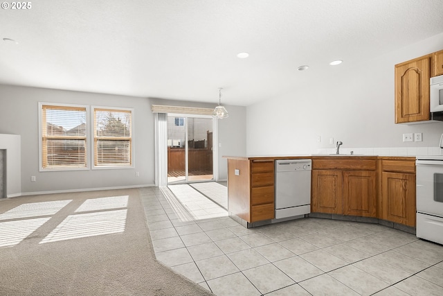 kitchen with brown cabinets, white appliances, light countertops, and decorative light fixtures