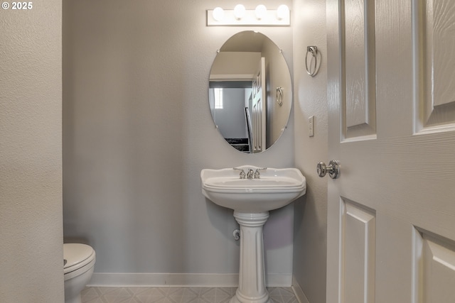 bathroom featuring toilet and baseboards