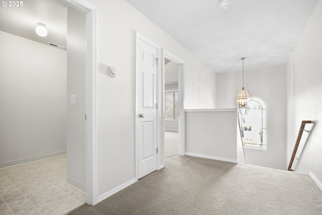 hall with light colored carpet, a notable chandelier, visible vents, baseboards, and an upstairs landing