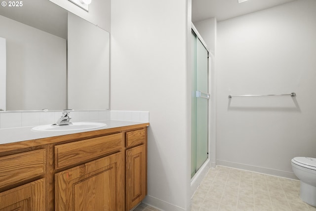 full bathroom featuring a stall shower, baseboards, vanity, and toilet