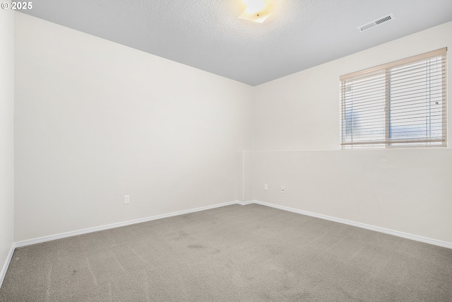 carpeted empty room featuring visible vents, a textured ceiling, and baseboards