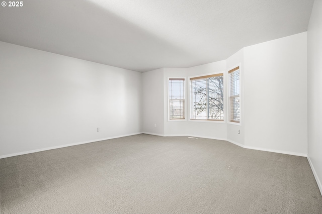 carpeted spare room featuring baseboards