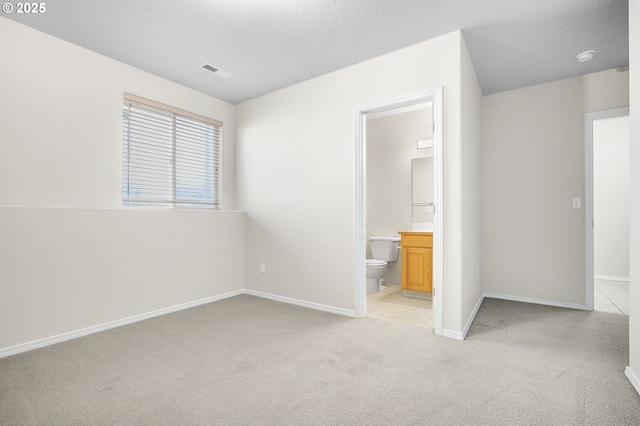 unfurnished bedroom featuring light carpet, a textured ceiling, visible vents, and baseboards