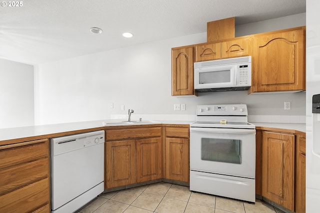 kitchen featuring white appliances, light tile patterned floors, light countertops, and a sink