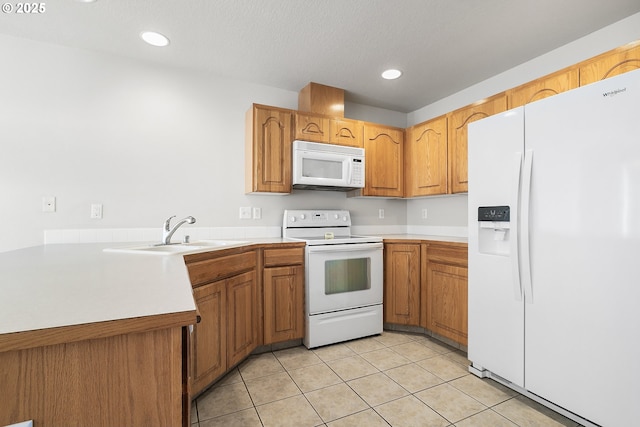 kitchen featuring light countertops, white appliances, brown cabinetry, and a sink