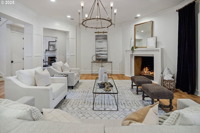 living area featuring an inviting chandelier, recessed lighting, wood finished floors, and a lit fireplace
