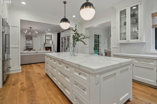 kitchen with white cabinetry, ornamental molding, light stone countertops, and a kitchen island