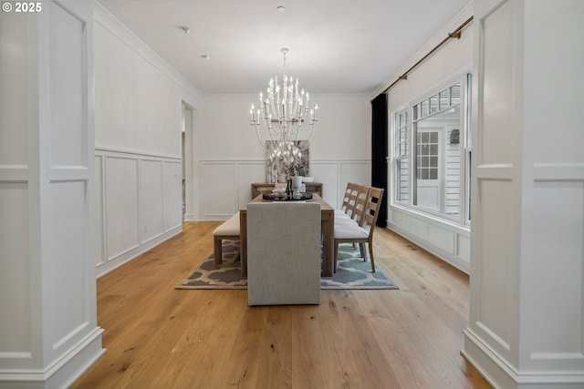 dining room with crown molding, light hardwood / wood-style floors, and a notable chandelier