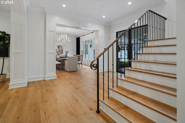 stairs featuring ornamental molding, hardwood / wood-style floors, and a notable chandelier