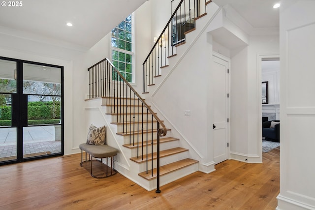 stairway with hardwood / wood-style flooring and ornamental molding