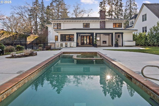back of property featuring fence, a chimney, a pool with connected hot tub, and a patio area