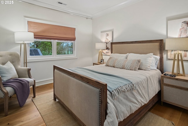 bedroom with ornamental molding and light hardwood / wood-style flooring