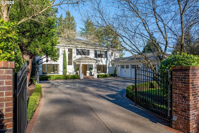 neoclassical home featuring fence, a gate, and driveway