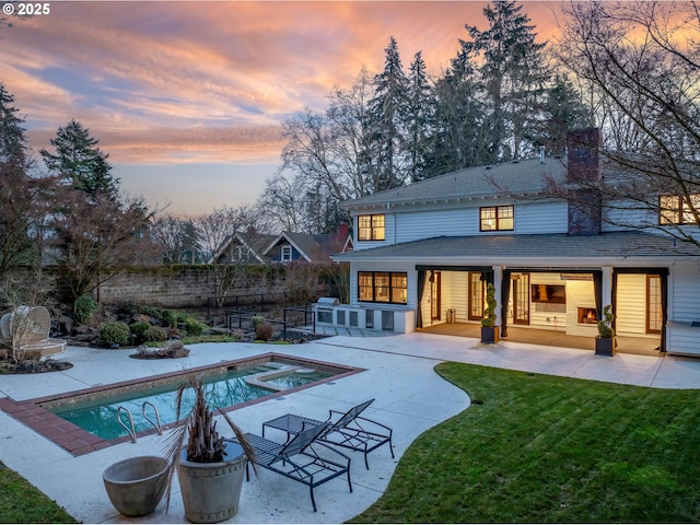 back house at dusk with a fenced in pool, a patio area, and a lawn