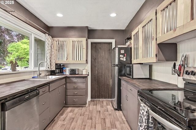 kitchen with appliances with stainless steel finishes, a sink, light wood finished floors, recessed lighting, and gray cabinets