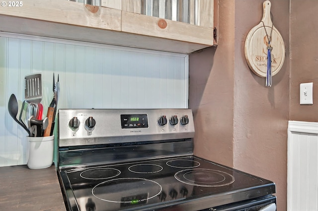 kitchen view of stainless steel range with electric stovetop and a textured wall