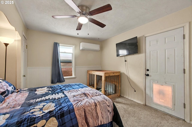 bedroom with a wall mounted AC, carpet floors, wainscoting, ceiling fan, and a textured ceiling