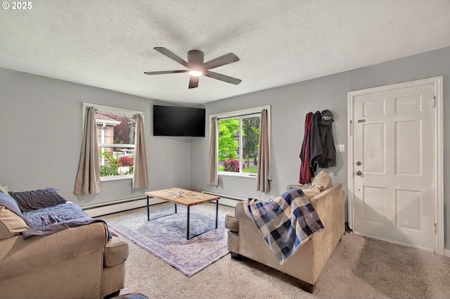 living area with a ceiling fan, baseboard heating, light colored carpet, baseboards, and a textured ceiling