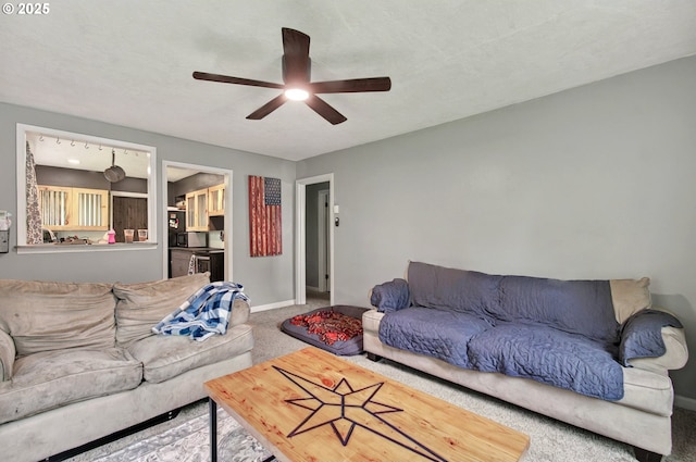 carpeted living area with ceiling fan and baseboards