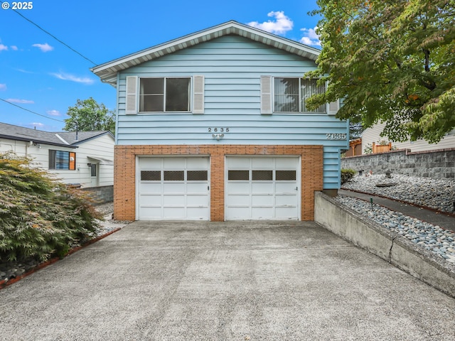 exterior space featuring a garage, concrete driveway, and brick siding