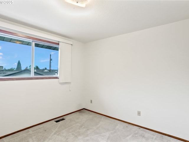 empty room featuring light carpet, visible vents, and baseboards