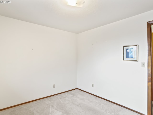 spare room with light carpet and baseboards