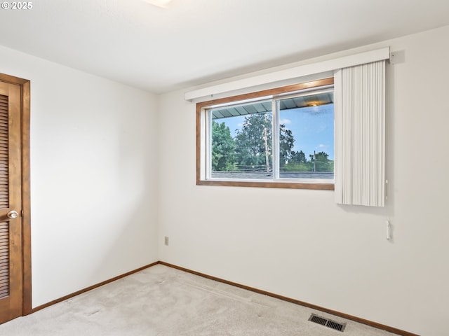 spare room with carpet floors, visible vents, and baseboards