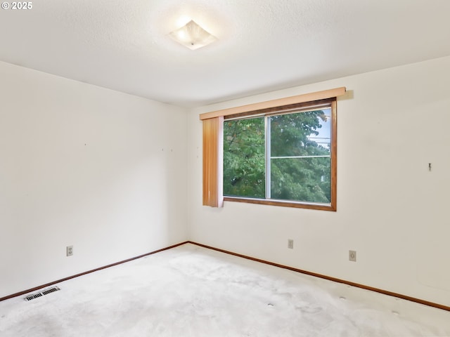 unfurnished room with baseboards, a textured ceiling, visible vents, and carpet flooring