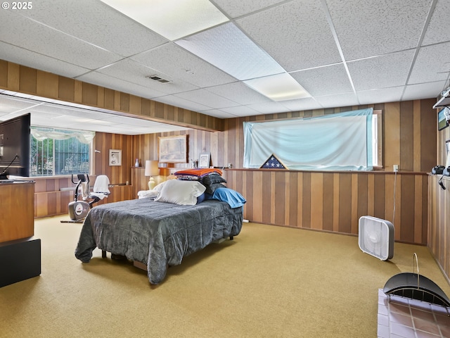 bedroom featuring a paneled ceiling, wood walls, visible vents, and carpet flooring