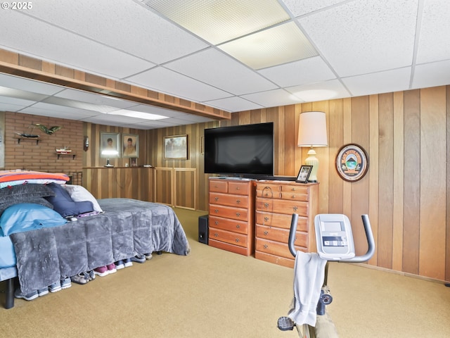 carpeted bedroom with a paneled ceiling and wood walls