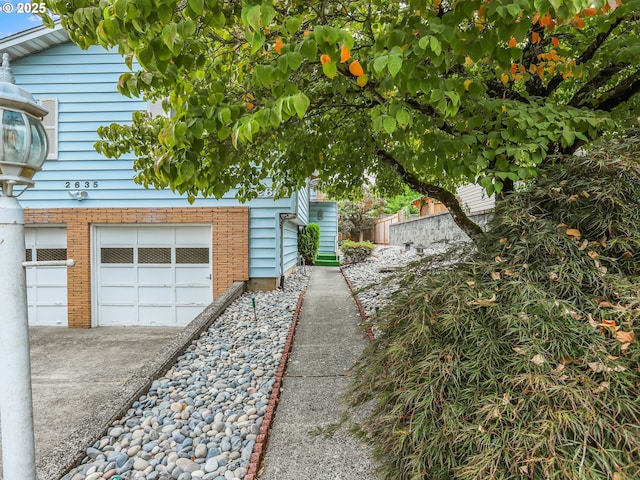 view of home's exterior featuring driveway, brick siding, and an attached garage