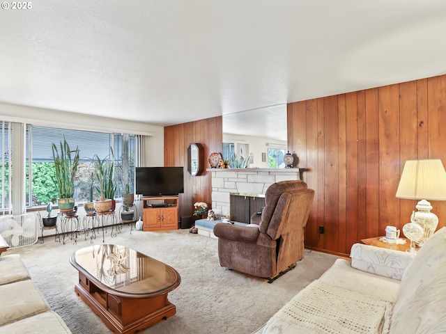 living room with light colored carpet, plenty of natural light, wood walls, and a fireplace