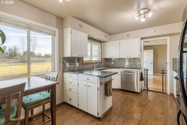 kitchen featuring hardwood / wood-style floors, dishwasher, white cabinetry, tasteful backsplash, and sink