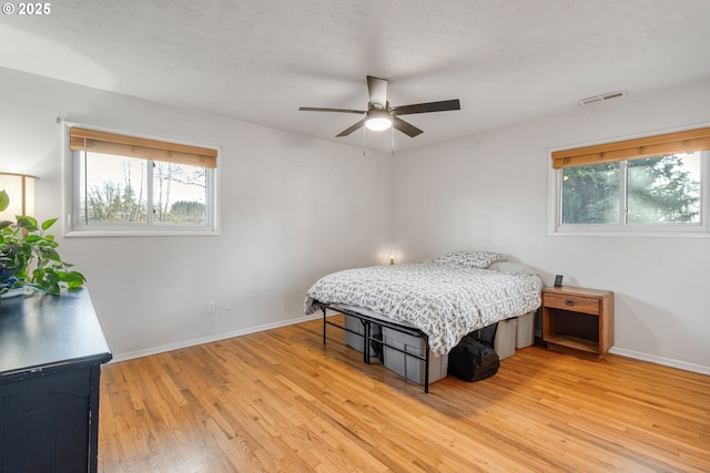 bedroom featuring light wood-type flooring, multiple windows, and ceiling fan