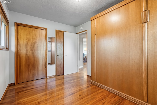 unfurnished bedroom with a textured ceiling and light hardwood / wood-style flooring