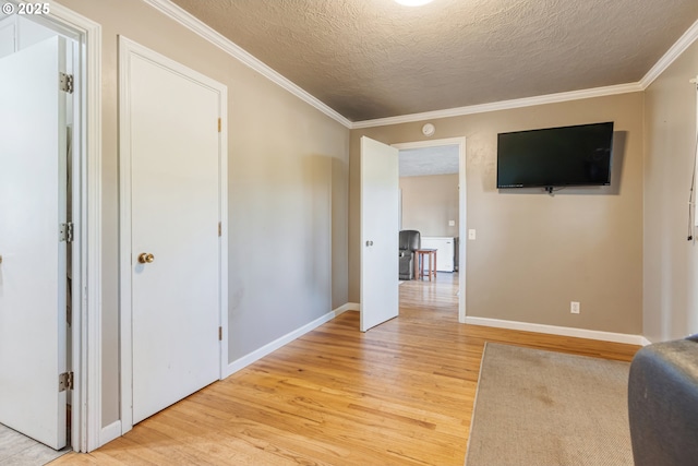 interior space with a textured ceiling, light hardwood / wood-style flooring, and ornamental molding