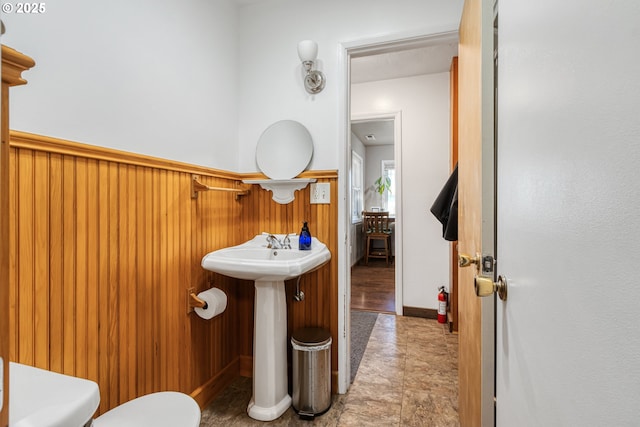 bathroom featuring toilet and wood walls