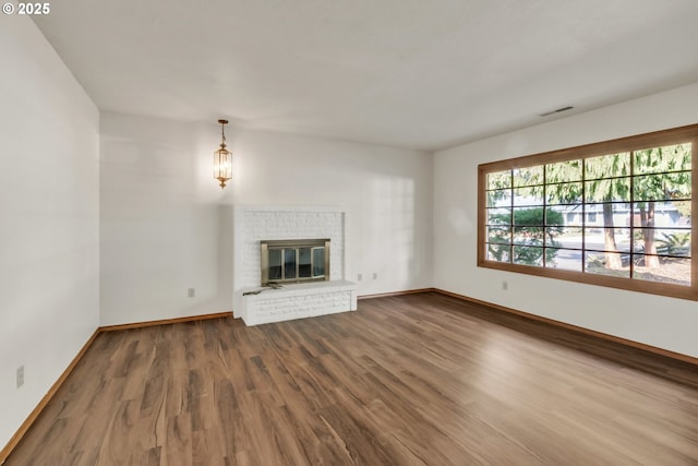 unfurnished living room featuring a brick fireplace and wood-type flooring