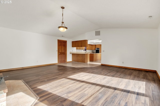 unfurnished living room with wood-type flooring, vaulted ceiling, and sink