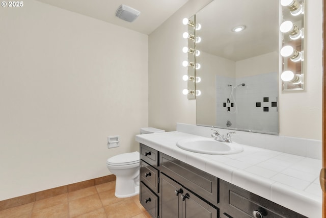 bathroom with vanity, a tile shower, tile patterned floors, and toilet