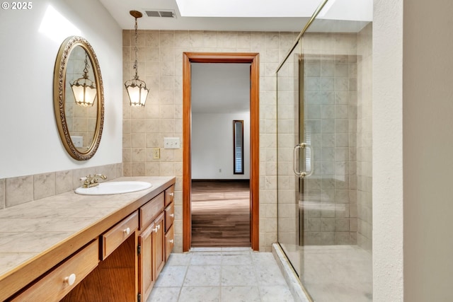 bathroom with vanity, tile patterned floors, tile walls, and walk in shower